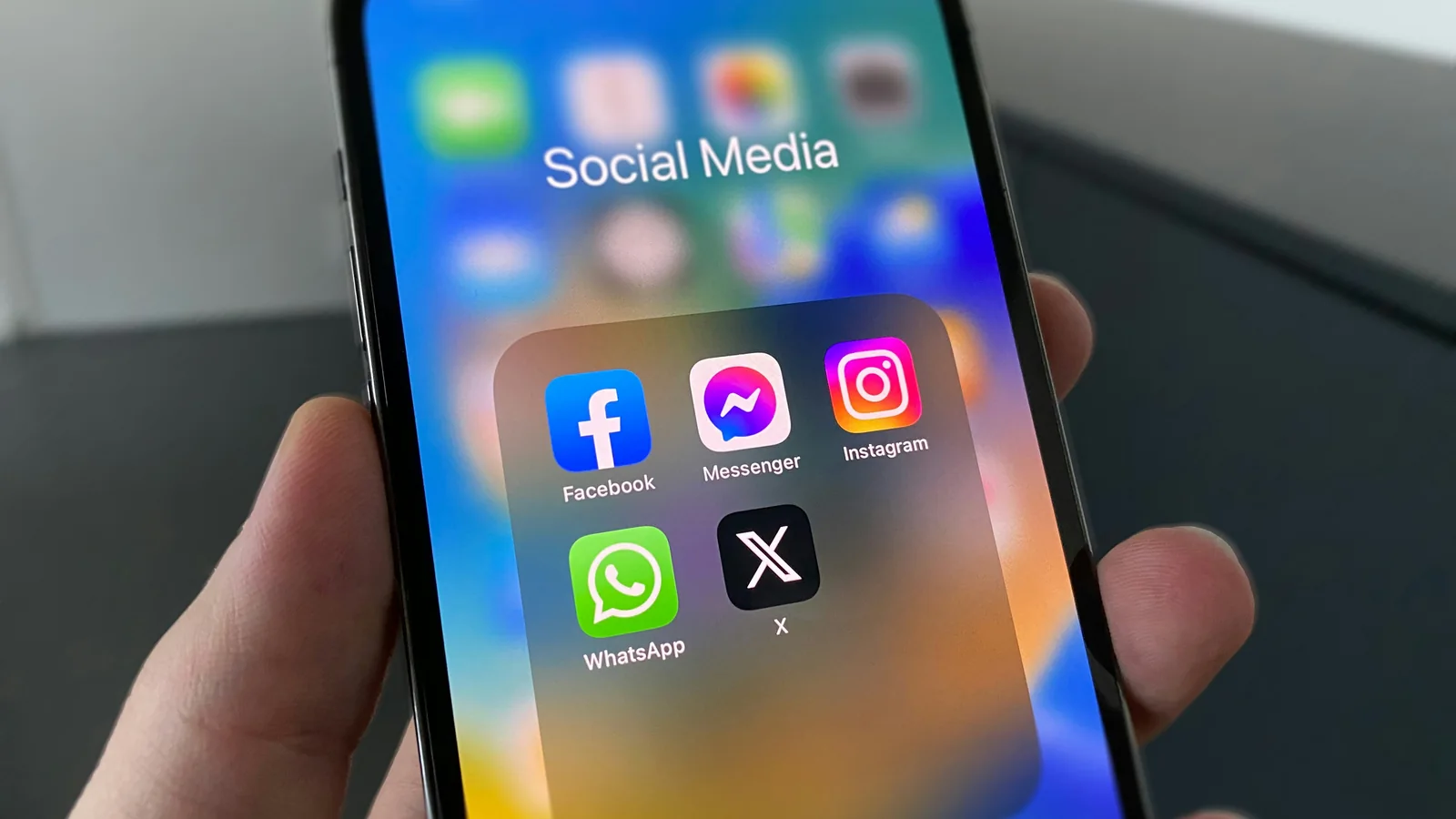 Uma mão segurando um smartphone com aplicativos de redes sociais, incluindo Instagram, na tela.